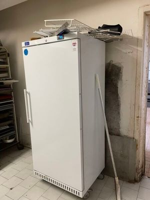 a white refrigerator in a room with a broom on the floor
