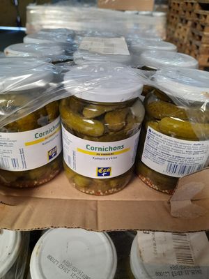 Plusieurs bocaux de cornichons sont posés sur une étagère dans un magasin