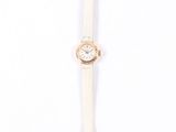 a white watch sitting on top of a white table next to a white wall