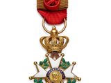 Gros plan sur une médaille sur fond blanc, accompagnée d'un ruban rouge