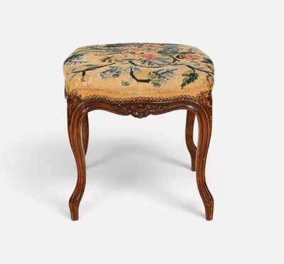 un petit tabouret en bois avec une assise rembourrée à motifs floraux