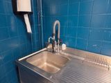 a stainless steel sink in the corner of a blue tiled bathroom