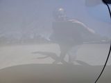 a man taking a picture of himself in the reflection of a car window