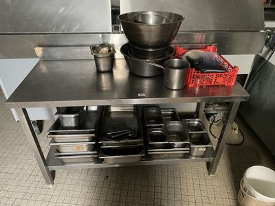 une table en métal sur laquelle sont posés des casseroles et des poêles