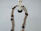 collier orné d'une statuette représentant une femme tenant une croix et un chapelet