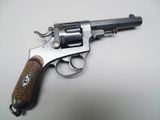 un vieux revolver avec une poignée en bois sur une surface blanche