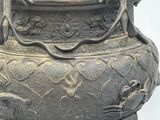 a large metal vase with a handle on a stand