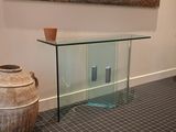 a glass table with a vase on it next to a painting