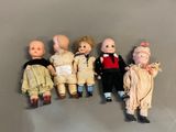 several dolls are lined up in a row on a gray surface