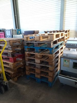 plusieurs palettes de bois sont empilées sur des palettes dans un entrepôt