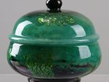 a green and black bowl with a lid on a table