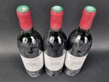 three bottles of red wine sitting next to each other on a table