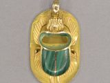 une photo d'un pendentif doré et vert orné d'une scarra