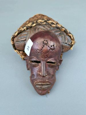 une image représentant un masque en bois coiffé d'un chapeau