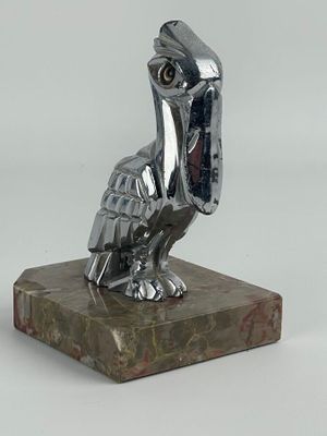 statue d'un pélican posée sur un socle en marbre, sur fond blanc