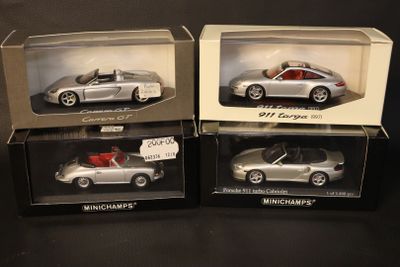 three boxed silver model cars in boxes on a black surface