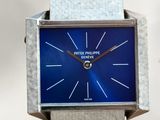 a silver watch with a blue face sitting on a table