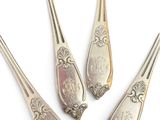 five silver spoons and a fork on a white surface