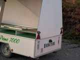 a small white truck with a green top parked on the side of the road
