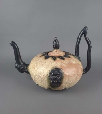 une théière noire et blanche posée sur une surface grise