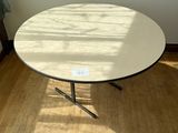 une table blanche au plateau noir posée sur un parquet en bois dur
