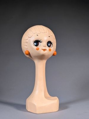 une petite poupée à la grosse tête posée sur un socle