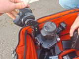 a person holding a camera in a bag with other items