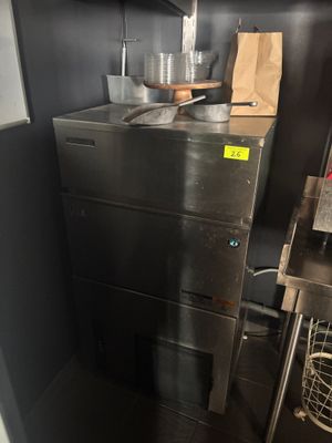 une armoire métallique placée dans un coin de la cuisine, sur laquelle sont posées des casseroles et des poêles