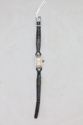 gros plan d'une montre sur une surface blanche avec un bracelet noir