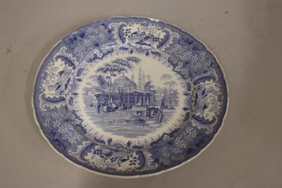 a blue and white plate with a picture of a village on it