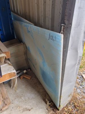 un tas de bois à côté d'une porte bleue