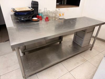 une grande table en acier inoxydable au milieu d'une cuisine