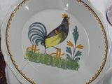 a plate with a rooster painted on it sitting on a table