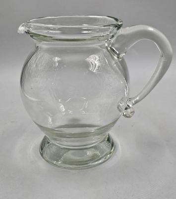 a clear glass pitcher with a handle on a table