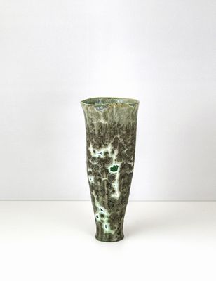un vase vert posé sur une table blanche