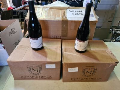 trois bouteilles de vin posées sur des cartons, sur une table