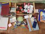 une boîte en bois remplie de fournitures scolaires posée par terre