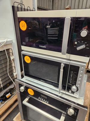 trois micro-ondes empilés les uns sur les autres dans un entrepôt