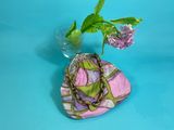 a vase with a flower and a purse on a table