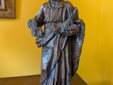 statue d'un homme tenant un panier de fleurs posé sur une table en bois