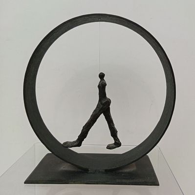sculpture of a man walking inside a circular object on a table