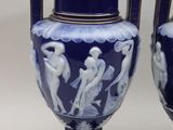 pair of blue vases with figures on them sitting on a white surface