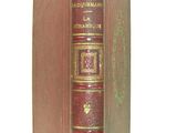an old red book with gold trim sitting on top of a white surface