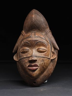 un gros plan d'un masque en bois posé sur une surface noire