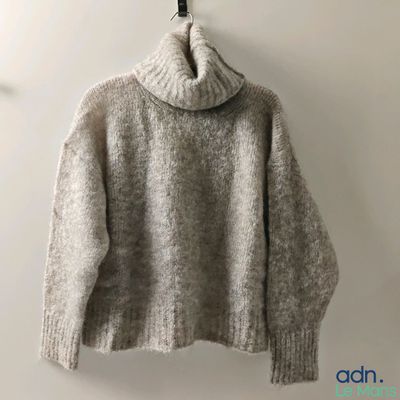 Le pull est suspendu à un cintre accroché au mur.