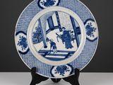 une assiette ancienne bleue et blanche représentant un homme dans une pièce