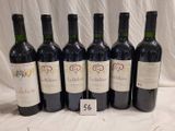 six bottles of wine are lined up in a row on a table