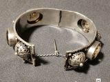 silver bracelet with bells and bells attached to it on a gray surface