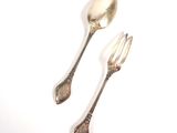 two silver spoons and a fork on a white surface