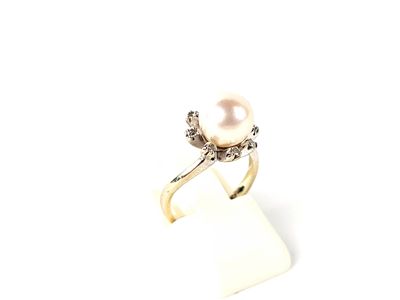 un gros plan d'une bague en perle blanche et diamants posée sur une surface blanche